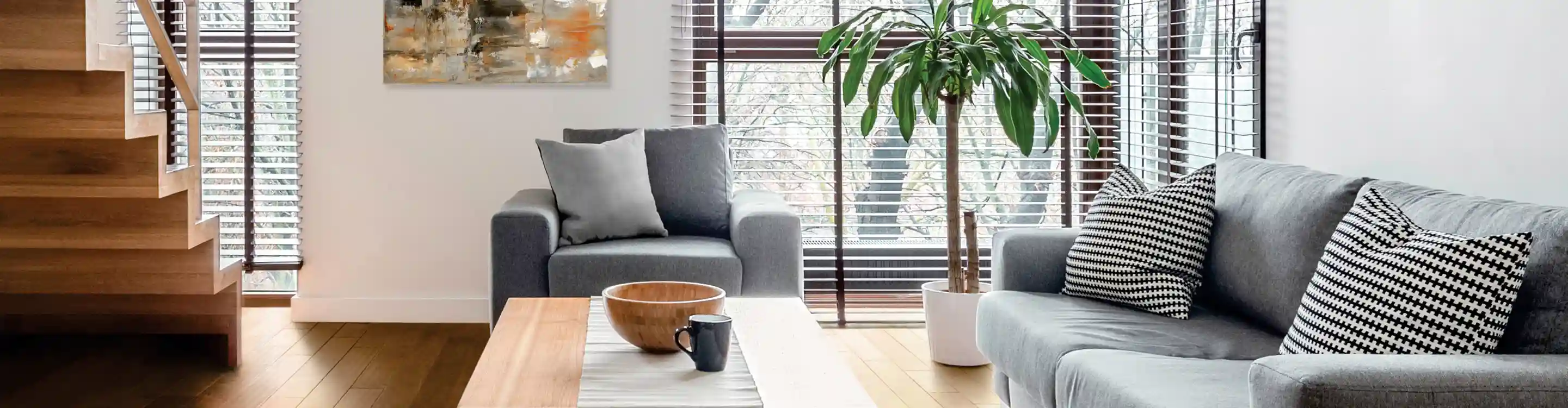 Graber dark brown blinds in living room with grey sofa and honey hardwood floors